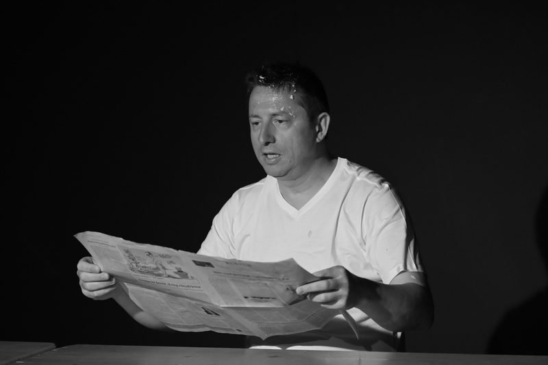 Am Tisch, mit der Zeitung.